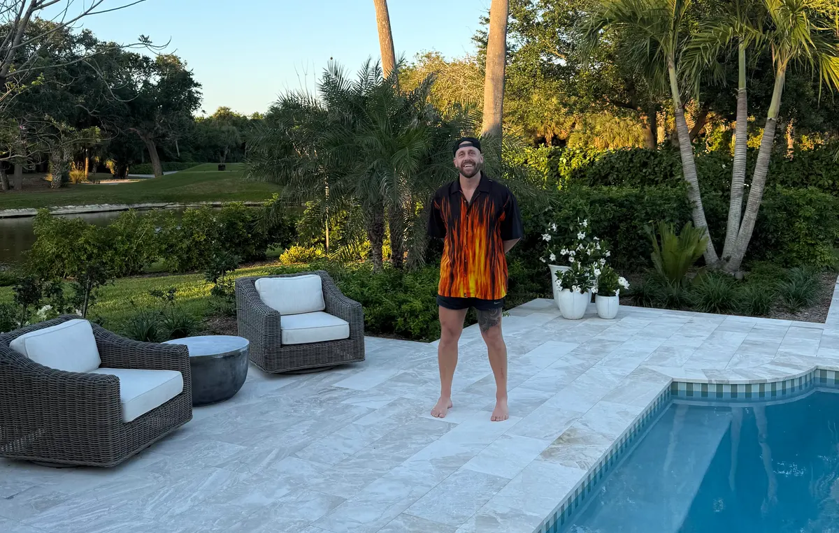 Michael standing barefoot on a pool deck in a flame-print shirt