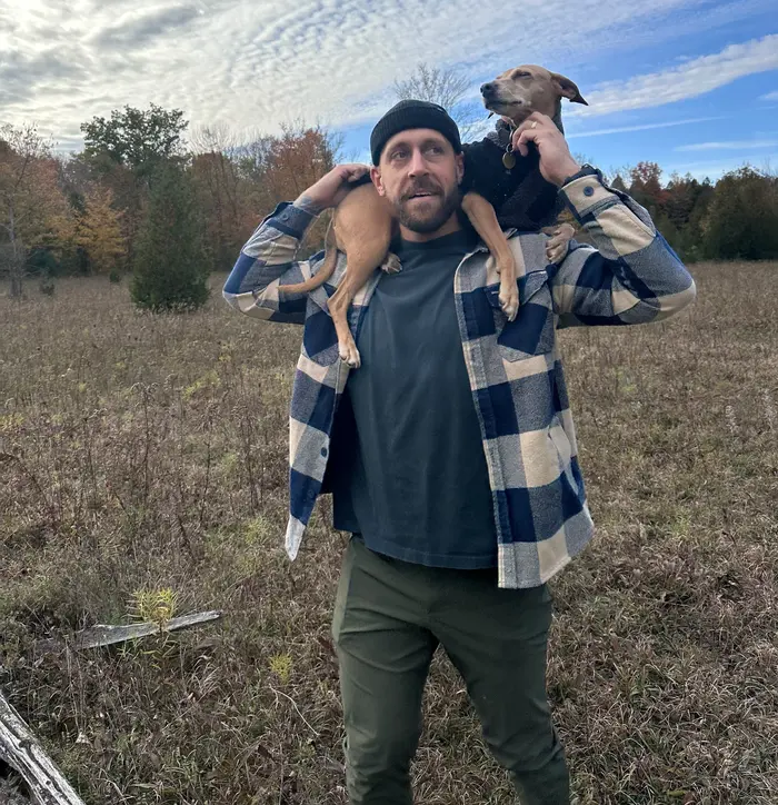 Michael in a field carrying his dog Rosie on his shoulders